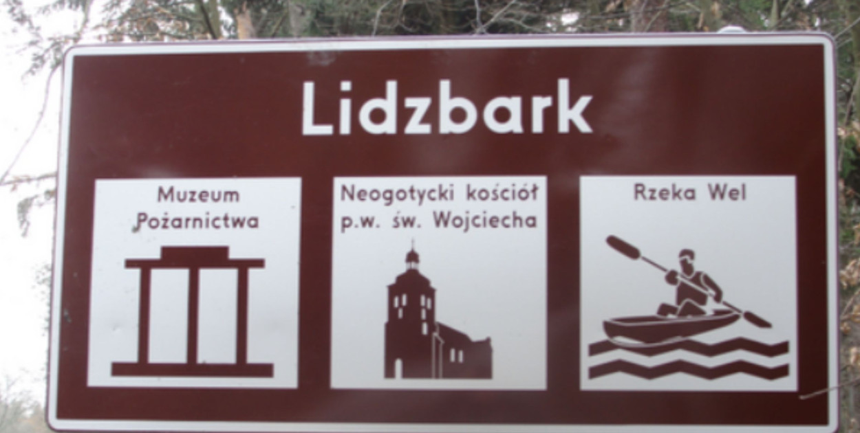 Tablica turystyczna Lidzbarka Welskiego – Muzeum Pożarnictwa, kościół św. Wojciecha i spływy kajakowe po rzece Wel.
